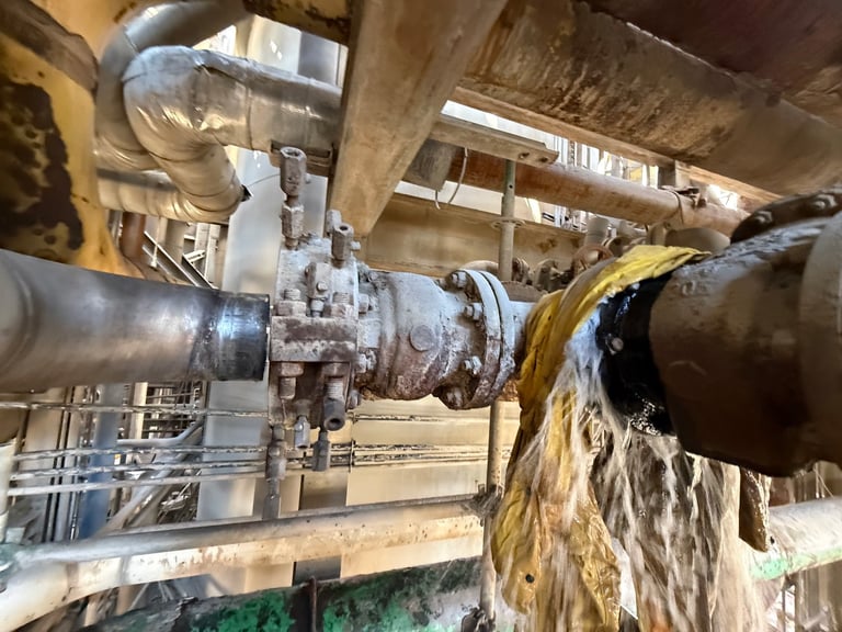 Industrial pump system with oil flowing from large metal pipes in a factory or processing facility