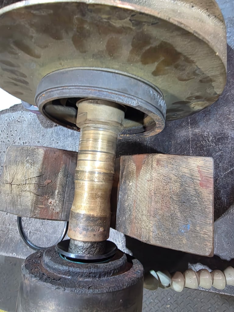 Close-up of a worn metal pulley system with brass fittings, wooden blocks, and deteriorated mechanical components